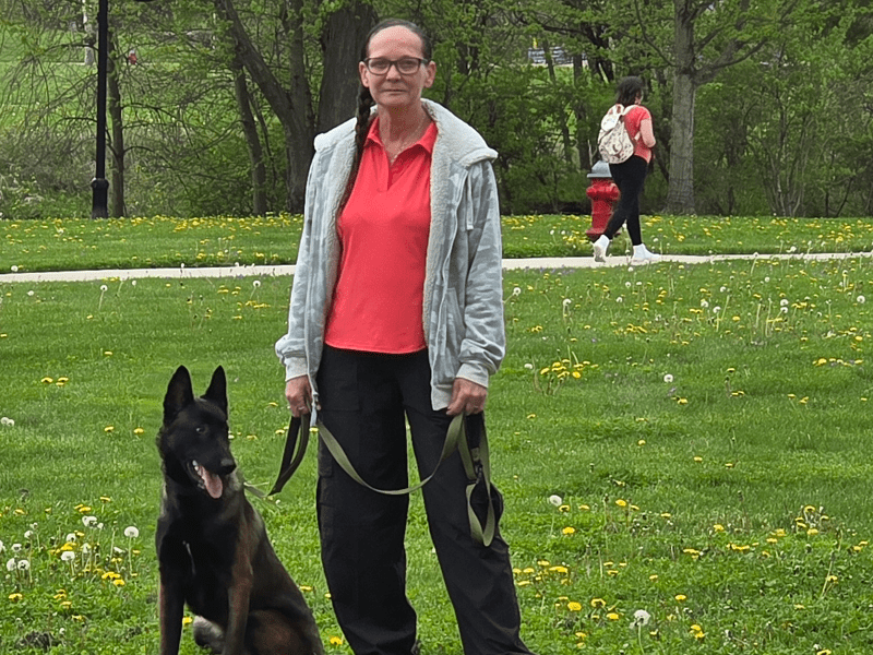 Man standing with a German Shepherd dog in a park.